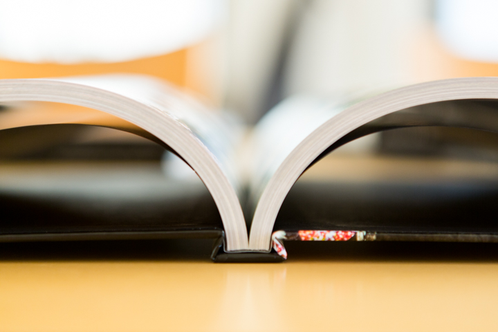 A close view of an open coffee-table book shows its binding and curved pages.