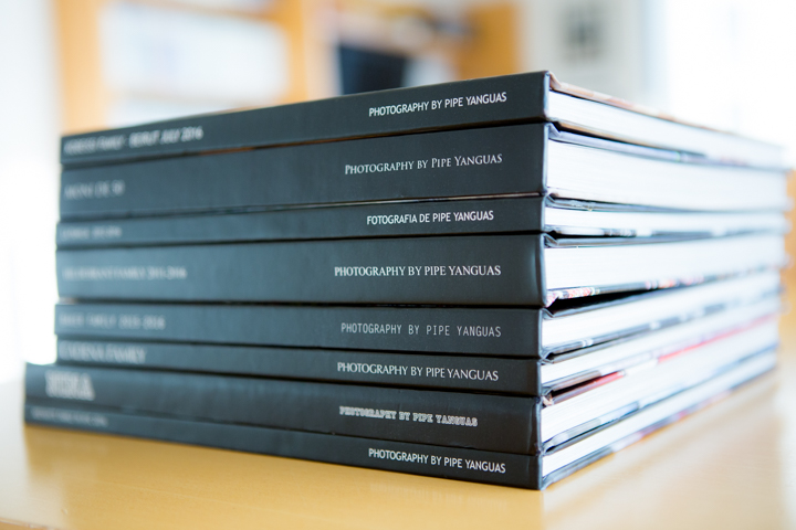 A stack of black PHOTObiography books rests on a table.