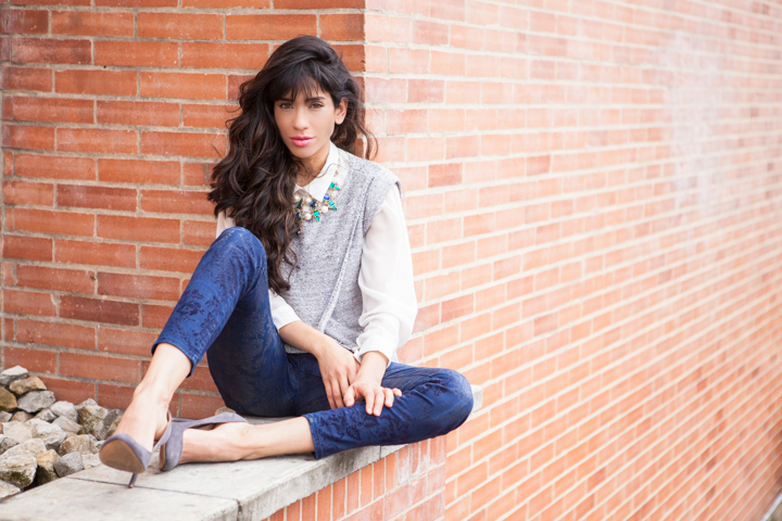 Woman sitting beside a brick wall
