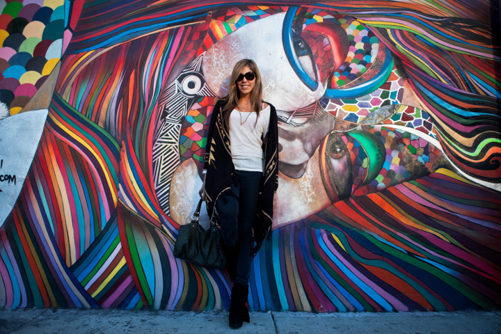 A woman stands in front of a brightly colored street mural.