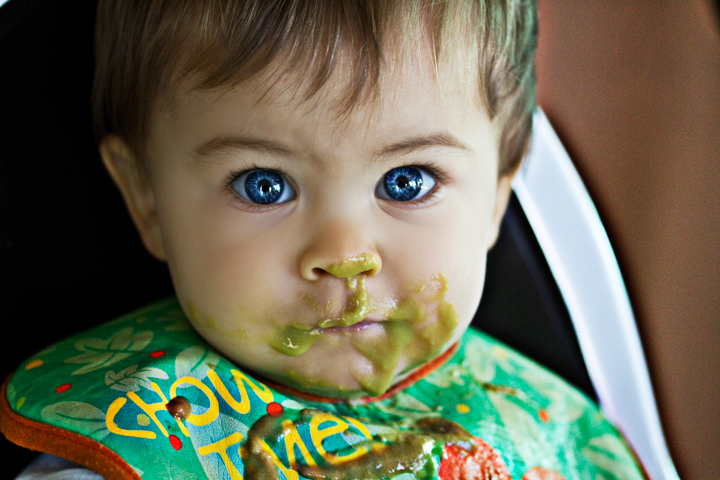 A child sits in a high chair with food around their mouth.