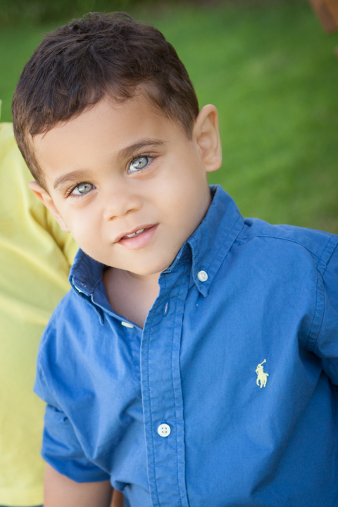 A child in a blue shirt stands on green grass.