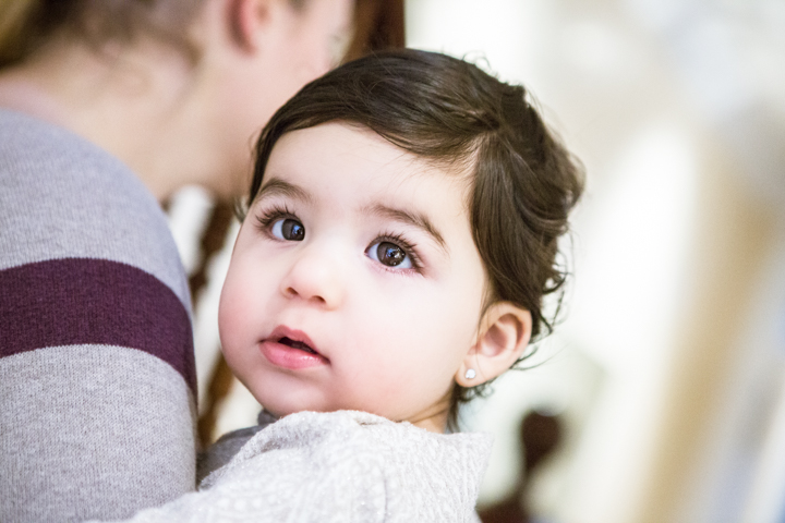 A young child rests against an adult's shoulder.