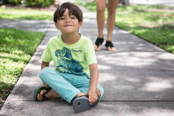 A child sits cross-legged on a garden path.