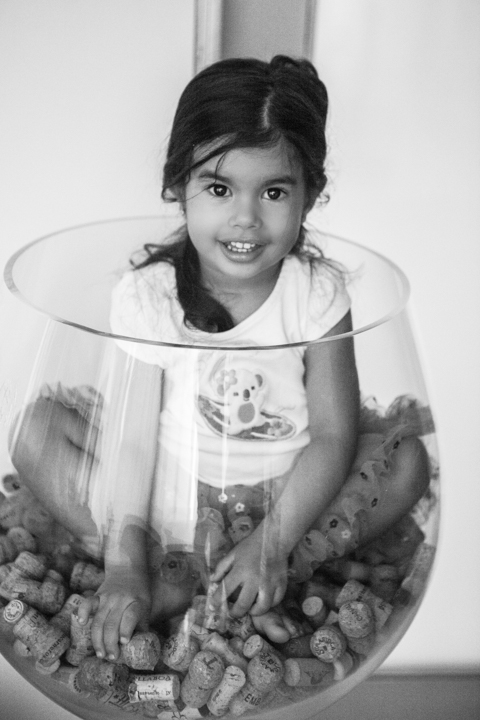 A child looks through a large glass bowl in a black-and-white portrait.