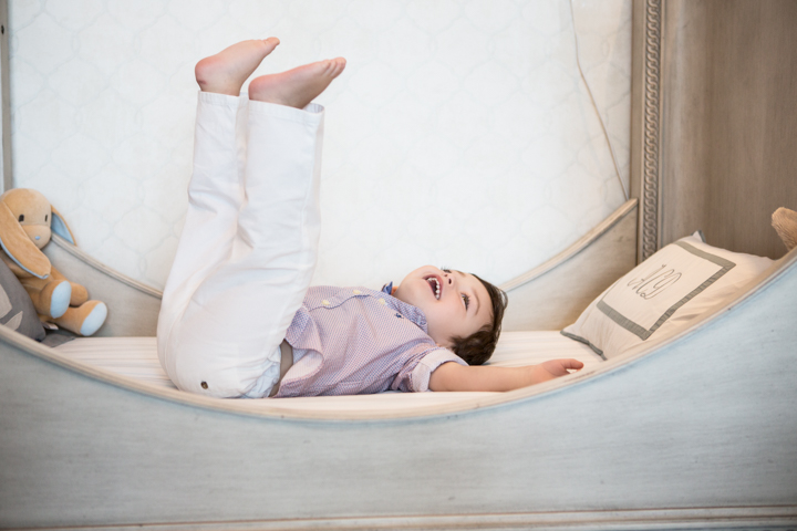 A child lies on a sofa with legs lifted and arms stretched overhead.