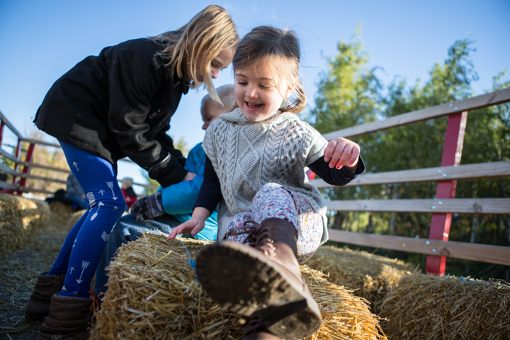 An adult steadies a laughing child on a wooden park bench.