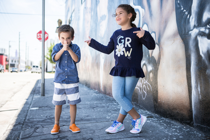 Two children stand beside a painted city wall.