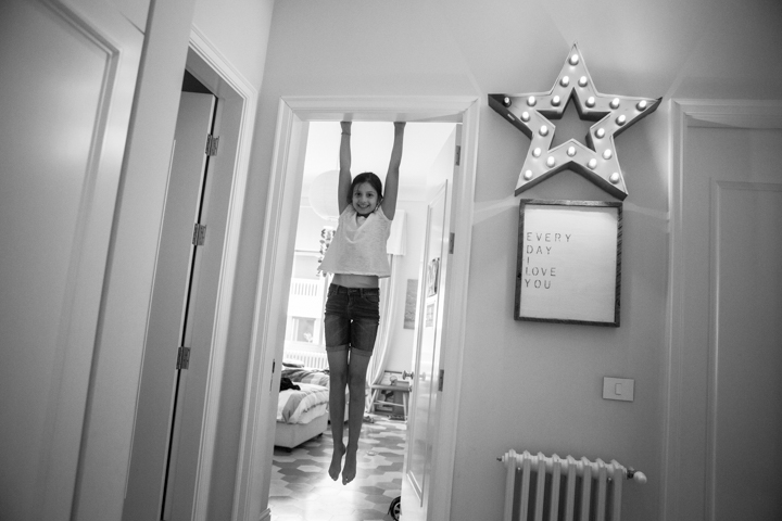 A child jumps in an indoor doorway in a black-and-white photograph.