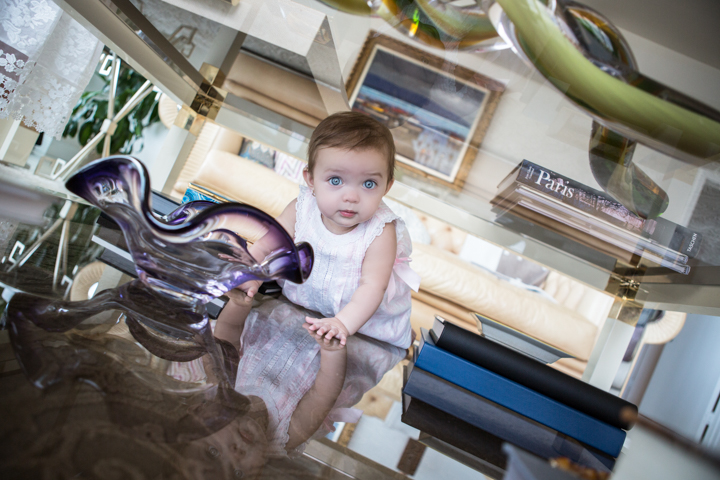 A toddler sits on a decorative metal chair indoors.