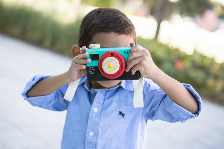 A child holds a colorful toy camera up to their face.