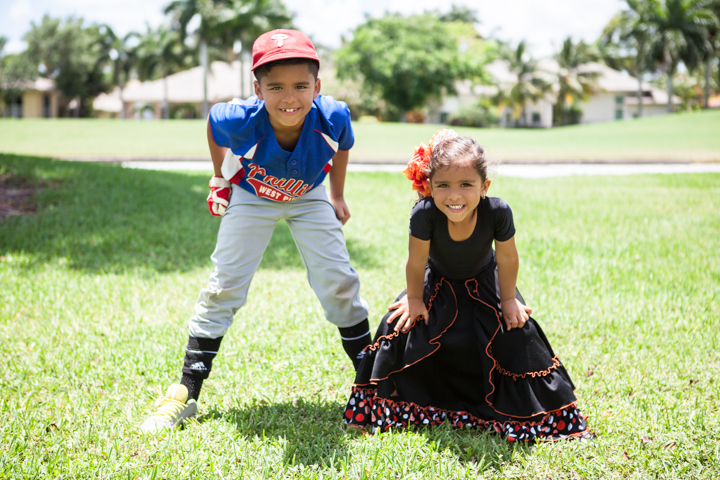 Two children in colorful outfits pose together on green grass.