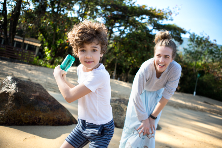 A child holds a green ice pop while a smiling woman leans forward behind them.
