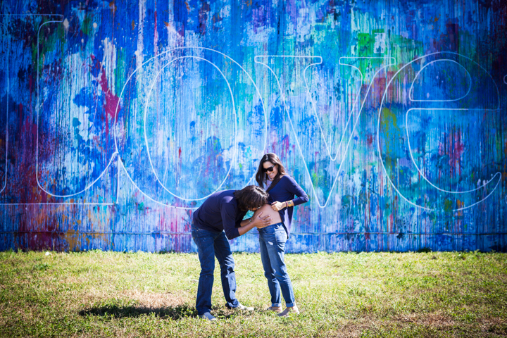 Two adults dance together in front of a large blue mural.