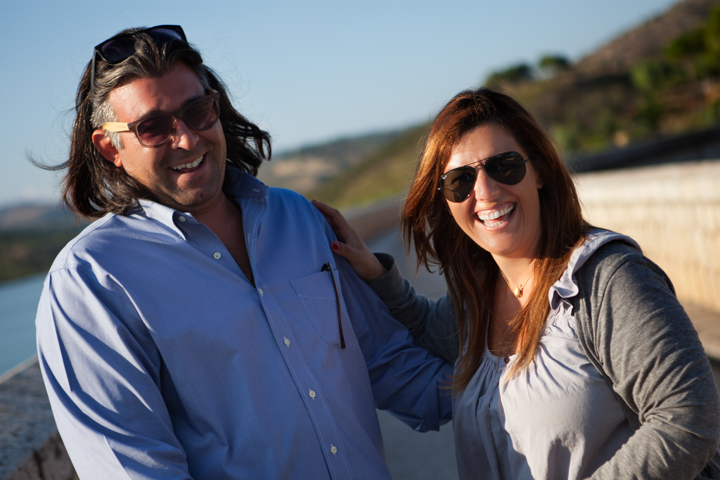 Two adults in sunglasses smile together outdoors.