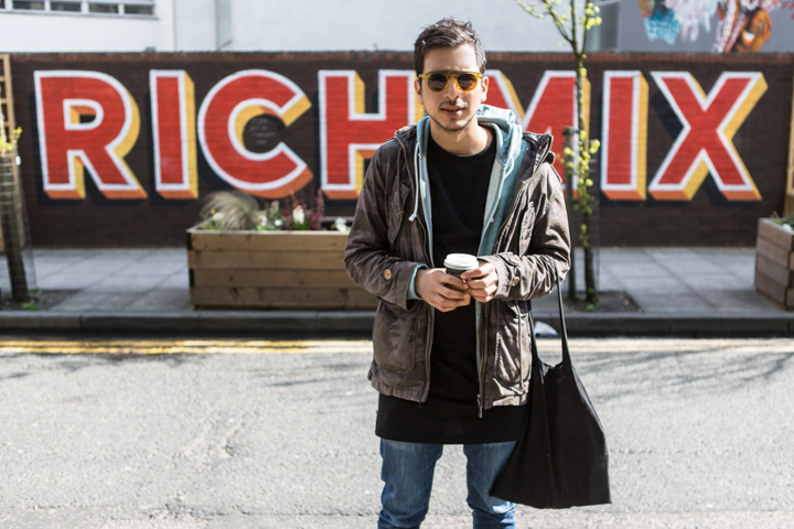 A man holding a camera stands in front of large colorful lettering.