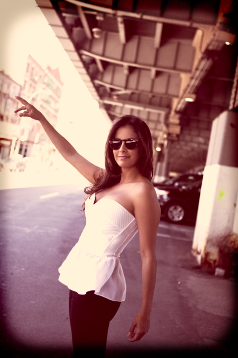 A woman in a white top stands beneath an overhead structure.