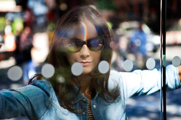 A woman in a denim jacket seen through a reflective shop window.