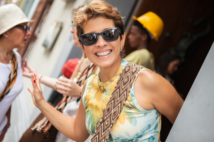 A smiling woman in sunglasses stands among friends outdoors.
