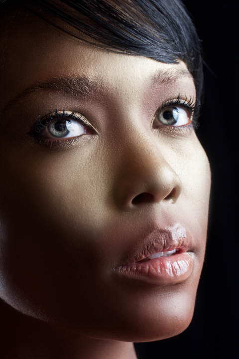 A close portrait of a woman looking upward in soft light.