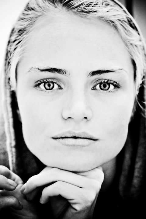 A close portrait of a woman resting her chin on her hand.