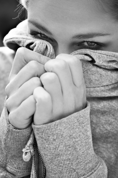 A woman holds her scarf over the lower part of her face.