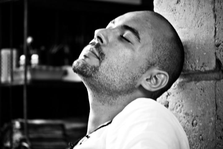 A man with his eyes closed leans his head against a wall.
