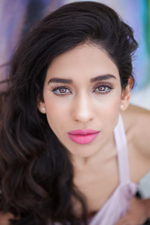 A close portrait of a woman with long dark hair and pink lipstick.