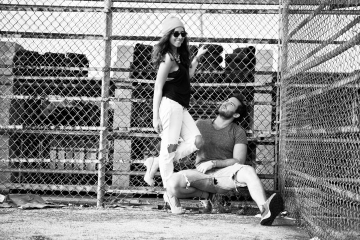 Two adults pose beside a metal fence in a black-and-white photograph.