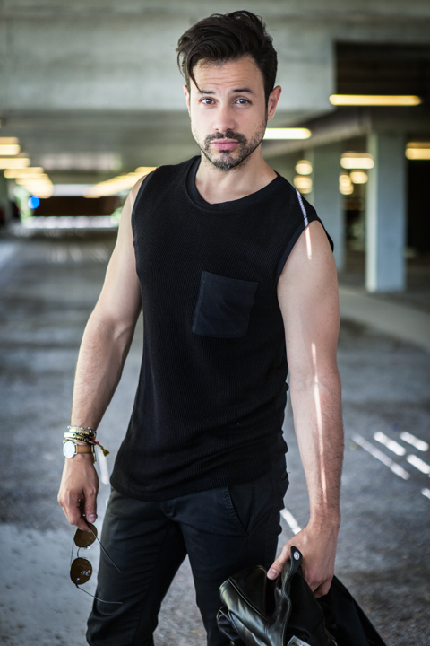 A man in a black sleeveless top carries a bag through an indoor passage.