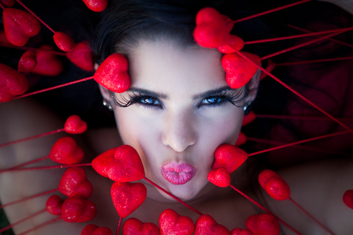A woman's face is framed by small red hearts on slender stems.