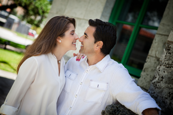 Two adults smile face to face while sitting together in a garden.