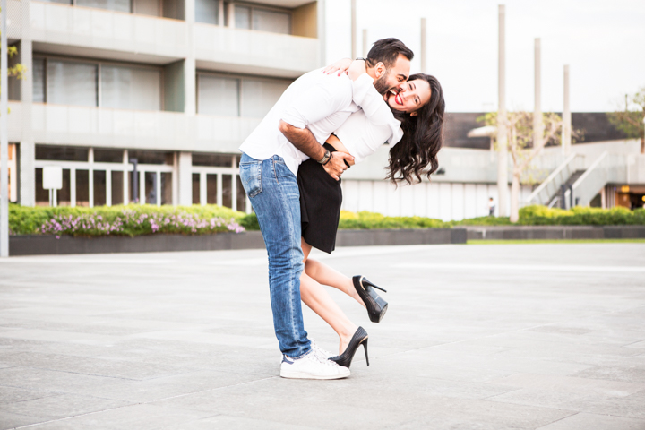 A man lifts a woman into an embrace outside a house.