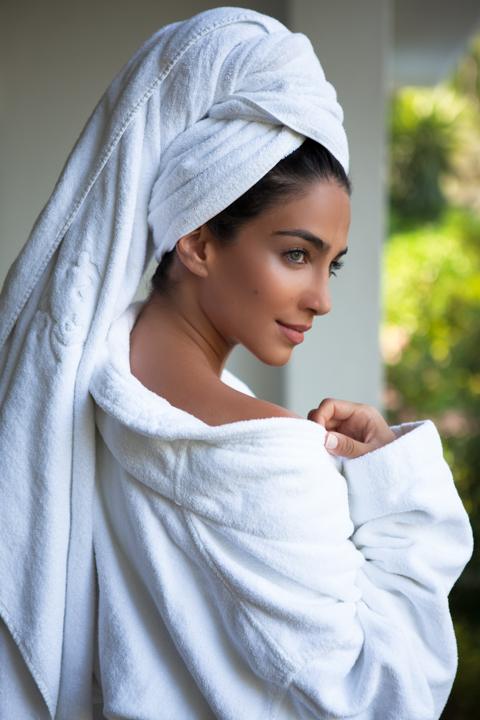 A woman wearing a white head wrap looks to the side outdoors.
