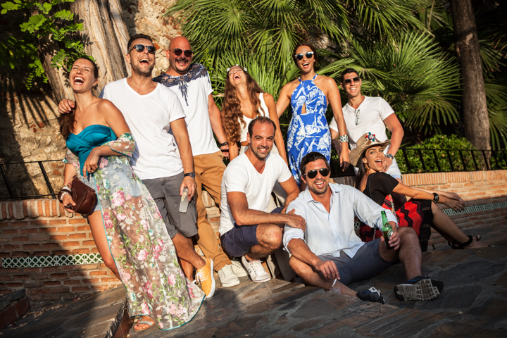 A group of adults gathers for a portrait beside tropical plants.