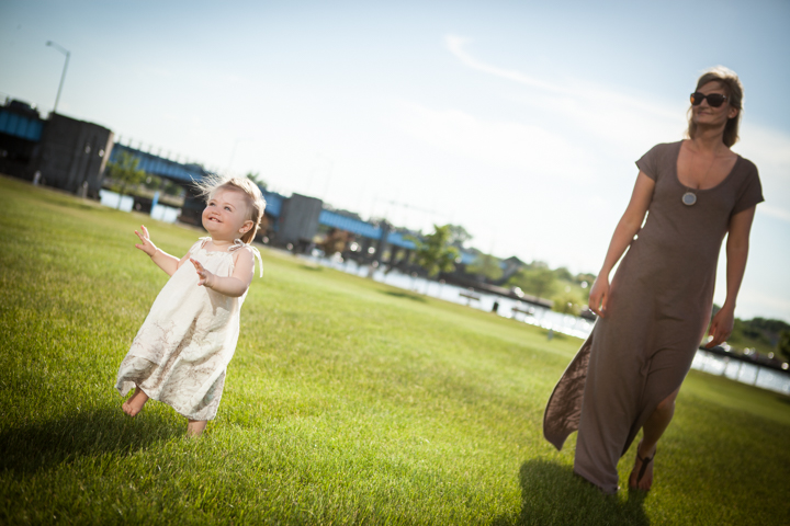 A woman and child walk across a sunny lawn.