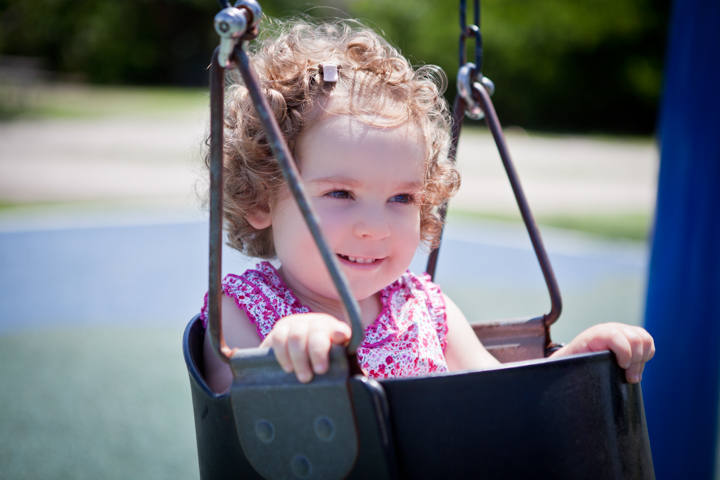 A young child sits in a playground swing.