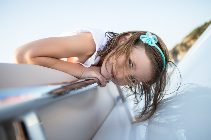 A child rests their cheek on folded hands beside the edge of a swimming pool.