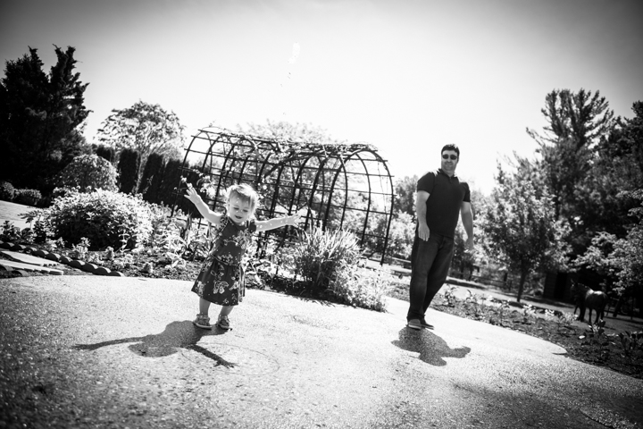 An adult and two children walk along a garden path in black and white.