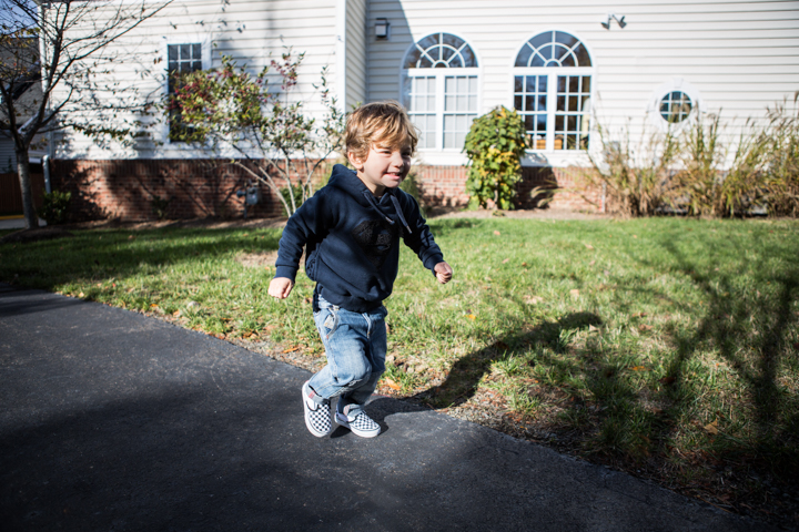 A child runs along a path outside a house.