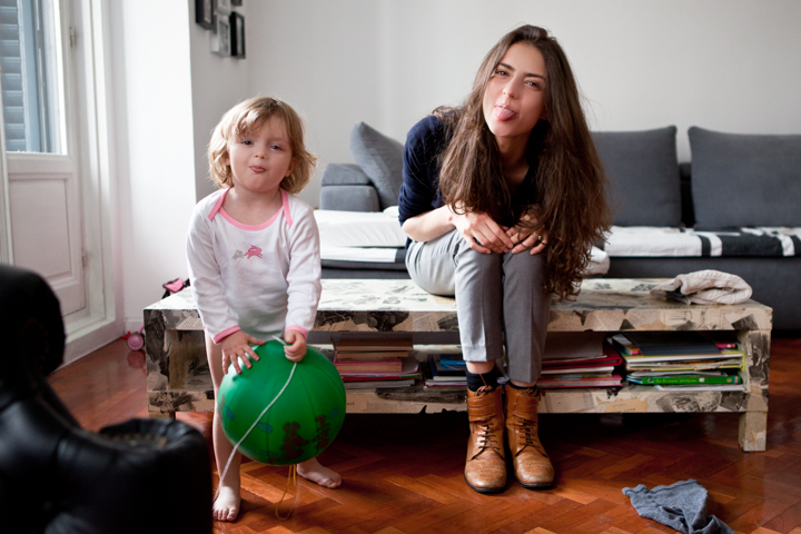 A woman and child sit together in a living room beside a green ball.