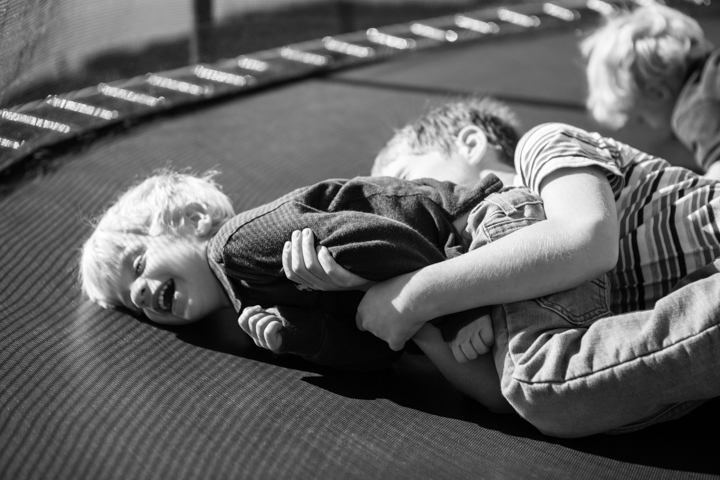Two children tumble together on a soft surface in black and white.