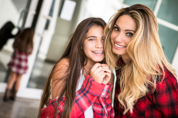 A woman and child wearing red plaid lean close together indoors.