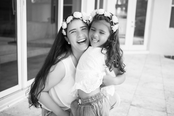 A woman and child wearing flower crowns hug in black and white.