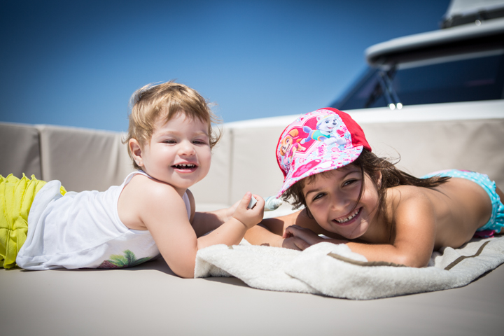 Two children lie together on a towel beside a boat.