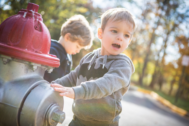 Two young children play beside a red fire hydrant.