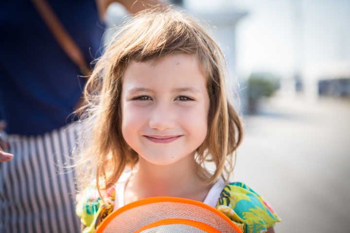 A smiling child holds a bright orange toy outdoors.