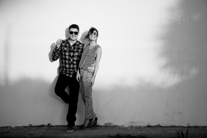 Two adults wearing sunglasses lean together in a black-and-white portrait.