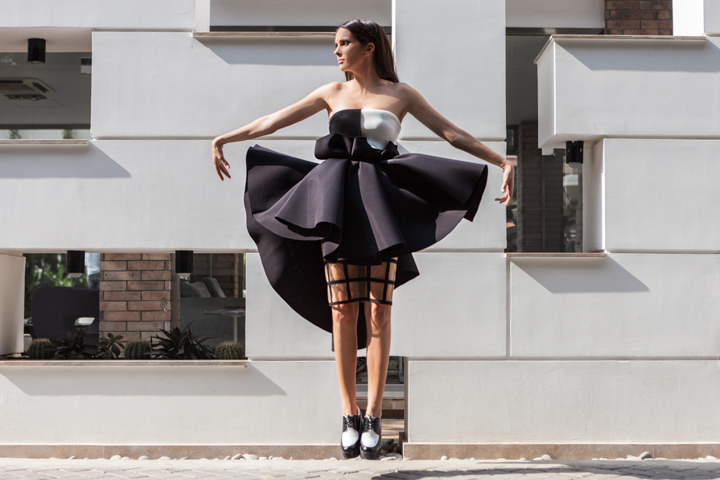 A dancer spreads a black skirt while standing on pointe outdoors.
