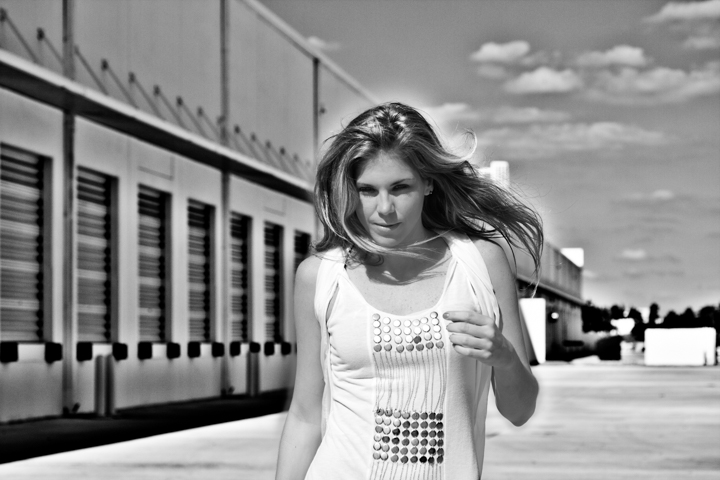 A woman walks beside an industrial building in a black-and-white portrait.